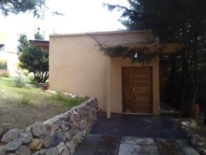 un pequeño edificio con una puerta marrón junto a una pared de piedra en Las Moras en Villa Giardino