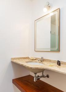 a bathroom with a sink and a mirror at Apartamento em Búzios com suítes e piscina |CLC 11 in Búzios
