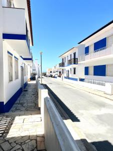 pusta ulica z biało-niebieskimi budynkami w obiekcie Apartamentos Guiomar Campos w mieście Porto Covo