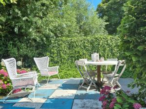 un patio con mesa, sillas y flores en Bed en breakfast Onder aan de dijk en Warder