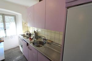 une cuisine avec des placards roses et un évier dans l'établissement Camera in Casa Eva, à Brione