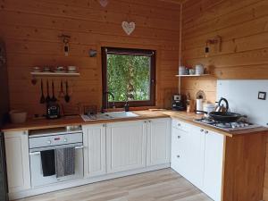 a kitchen with white cabinets and a sink and a window at Chata z Kraja in Pewel Wielka