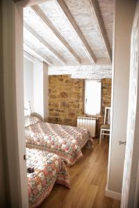 a bedroom with two beds and a brick wall at Apartamentos El Patio in Lerones