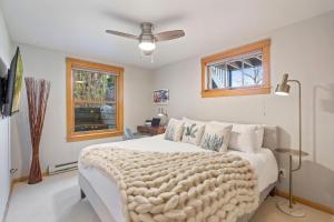 a bedroom with a white bed and a ceiling fan at Sleek Condo - Near Park, Poudre River and Old Town in Fort Collins
