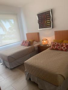 a hotel room with two beds and a window at Depa de lujo en Acapulco diamante con club de playa a pie-Precio especial in Acapulco +128 photos