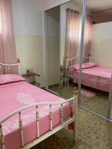 a bedroom with two beds with pink sheets and a mirror at Apartamentos Avenida in Praia