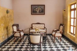 a living room with chairs and a table and a checkered floor at Casa Vicenta Izamal in Izamal