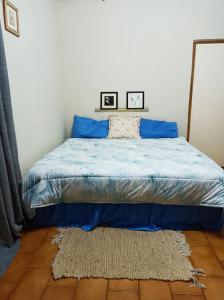 a bedroom with a bed with blue sheets and a rug at 18 on Shores in Pietermaritzburg
