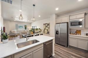 a kitchen with a sink and a stainless steel refrigerator at Modern Farmhouse Townhome - Great Central Location in Fort Collins