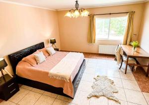 1 dormitorio con cama, mesa y ventana en Hotel El Almendro, en Paine
