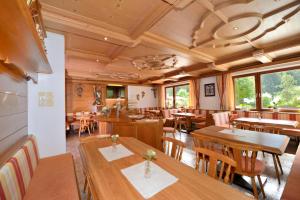 a restaurant with wooden tables and chairs and windows at Hotel Garni Bergwelt in Sankt Anton am Arlberg