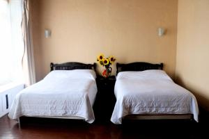 two beds with white sheets and a vase of flowers at Hotel Casa Blanca in El Oro de Hidalgo