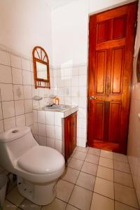 a bathroom with a toilet and a sink and a red door at BORUKA BnB in Alajuela