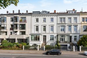 um carro preto estacionado em frente a um grande edifício branco em HOMEY Apartments - Riverside - mit Weserblick und Parkplatz em Bremen