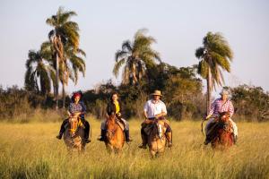 a group of people riding horses in a field at Estancia San Agustin in Curuzú Cuatiá