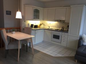 a kitchen with white cabinets and a table and a chair at Fischerstuuv in Husum