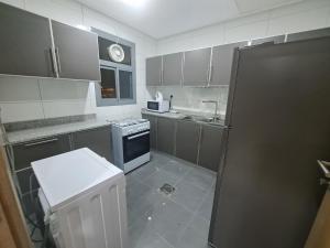 a kitchen with gray cabinets and a black refrigerator at Garden Dahlia Hotel Apartment - Formerly Regency Dahlia - Farwaniya in Kuwait