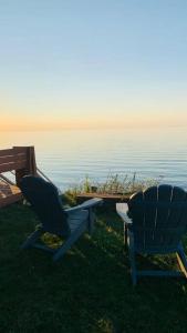 zwei Stühle auf dem Gras neben dem Wasser in der Unterkunft Lakefront Cottage w/ Private Beach- Niagara 