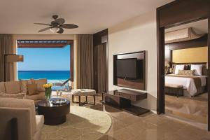a hotel room with a bed and a tv and a bedroom at Secrets Playa Mujeres Golf & Spa Resort - All Inclusive Adults Only in Cancún