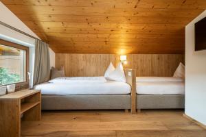 two beds in a room with a wooden ceiling at Apartments Untersüßgut Eben in Eben im Pongau