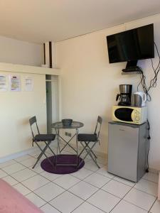 een keuken met een tafel en 2 stoelen en een magnetron bij Ladoré in Montjoly