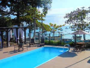 uma piscina com cadeiras, uma mesa e um guarda-sol em Hotel Pé na Areia em Penha
