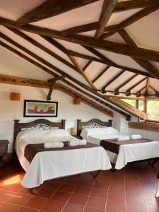 two beds in a room with wooden ceilings at Hotel, Bungalows, Chalet y Cabañas Aventura Park Villa De Leyva La Periquera in Villa de Leyva