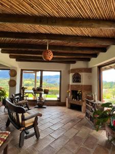 ein Wohnzimmer mit einem Tisch, Stühlen und Fenstern in der Unterkunft Hotel, Bungalows, Chalet y Cabañas Aventura Park Villa De Leyva La Periquera in Villa de Leyva