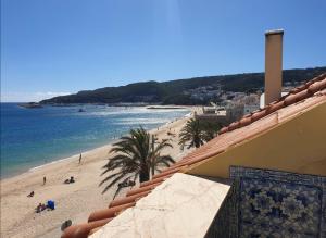 une vue sur une plage et l'océan depuis un immeuble dans l'établissement BLUE HOUSE SESIMBRA with parking, à Sesimbra