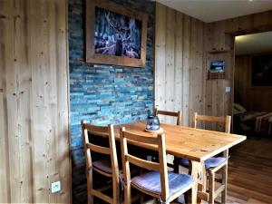 a wooden table and chairs in a room with a brick wall at Gîtes Le Cerf de Belledonne in Sainte-Agnès +49 photos