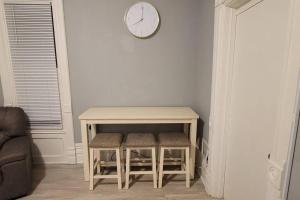 a table with two stools and a clock on a wall at Retreat Suite 1 - Cozy Downtown Getaway in Grand Rapids