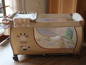 a baby crib with a cot with a toy at Ferienappartement Austen in Piding