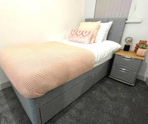 ein Schlafzimmer mit einem Bett und einem Nachttisch daneben in der Unterkunft SA Stays in Wigan