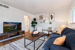 Una sala de estar con un sofá azul y un televisor. en Centrally Located Townhome Near PVH - Dog Friendly, en Fort Collins