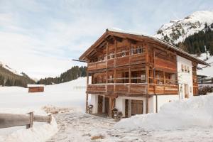 uma cabana de madeira na neve com neve à sua volta em Appartement Graf em Lech am Arlberg