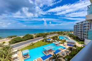 an aerial view of a resort with a pool and the ocean at Breath Taking Beach Front Views Condo Eagle Beach in Palm-Eagle Beach
