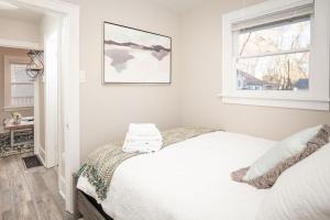 een witte slaapkamer met een bed en een raam bij Carriage House Walk to UNC + Free Bikes in Greeley