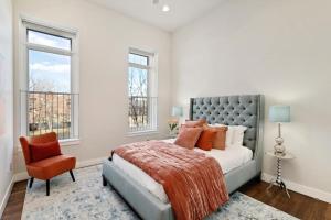 a bedroom with a bed and a chair and windows at The Penthouse Loft in the Heart of Old Town! in Fort Collins