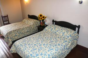 two beds in a room with a vase of sunflowers at Hotel Casa Blanca in El Oro de Hidalgo