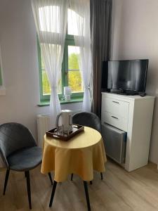 a living room with a table and a tv at Pokoje Pod Mniszkiem in Boguszów-Gorce