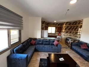 a living room with blue couches and a kitchen at Horizon22 in Wadi Musa