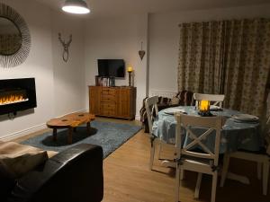 a living room with a table and a fireplace at Anvil Cottage in Mold