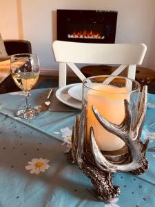 una mesa con una copa de vino y cuernos. en Anvil Cottage en Mold