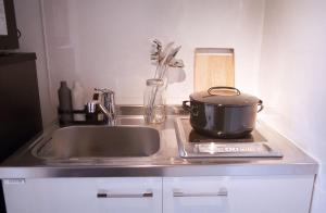 a kitchen counter with a sink and a pot on a stove at The Aoca Tokyo Sanno in Tokyo