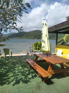 a picnic table with an umbrella and a picnic bench at VILLA DE LA BAIE RAIATEA in Uturoa