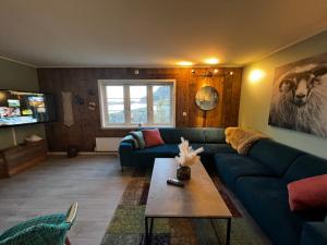 Sennesvik Apartments Lofoten في Sennesvik: غرفة معيشة مع أريكة زرقاء وطاولة