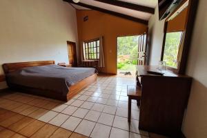 Schlafzimmer mit einem Bett, einem Schreibtisch und einem Fenster in der Unterkunft Hotel Villa Zurqui in San José
