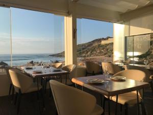 マセイラにあるPromar - Eco Beach & Spa Hotelの海の景色を望むテーブルと椅子付きのレストラン