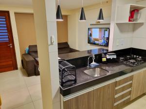 uma cozinha com um lavatório e uma televisão num quarto em Flat Tambaú Solar do Atlântico em João Pessoa