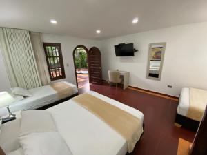 a hotel room with two beds and a television at Hotel Casa Colonial in Barranquilla